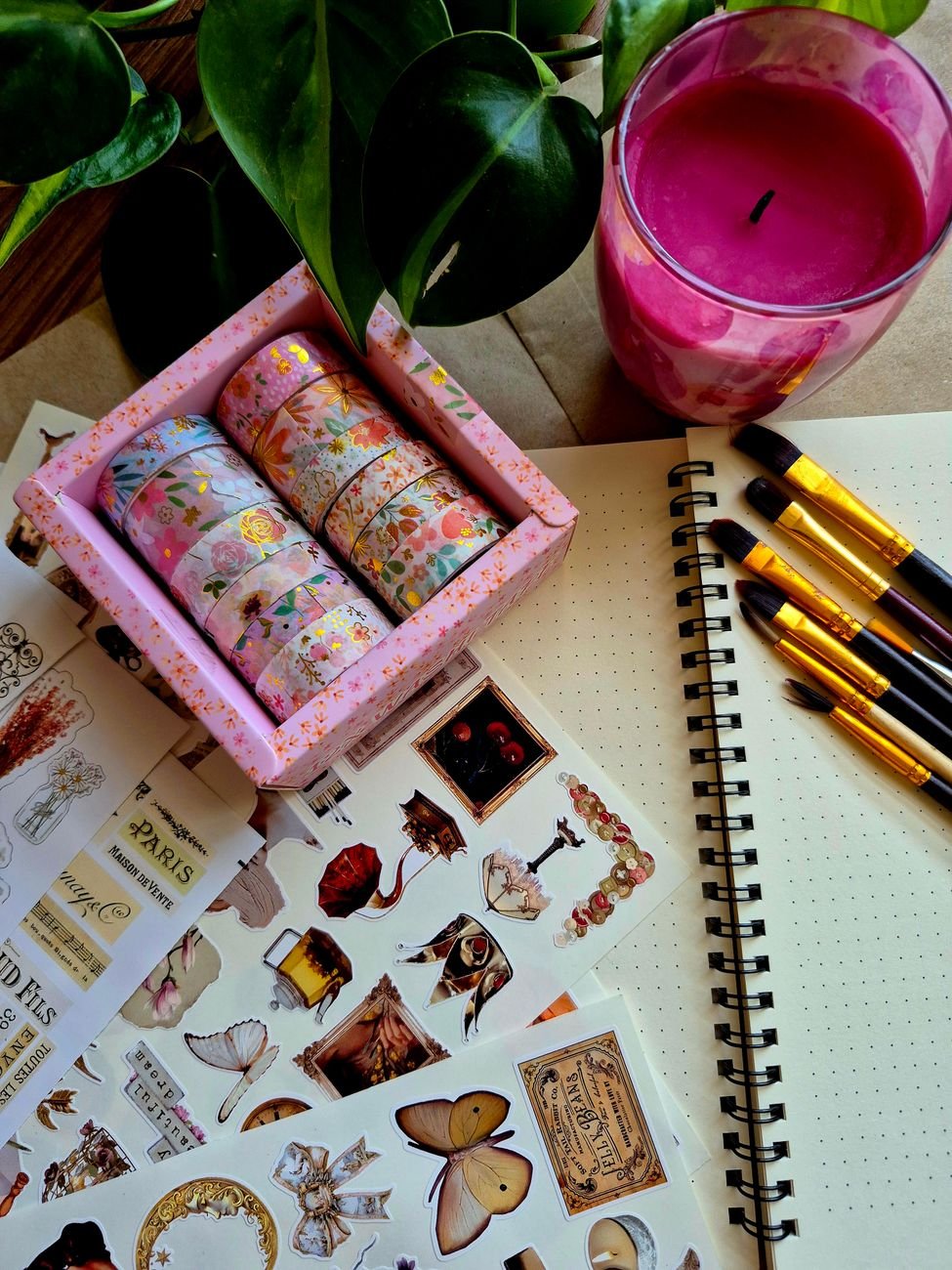 Artistic flat lay of journaling tools including stickers, washi tape, and brushes
