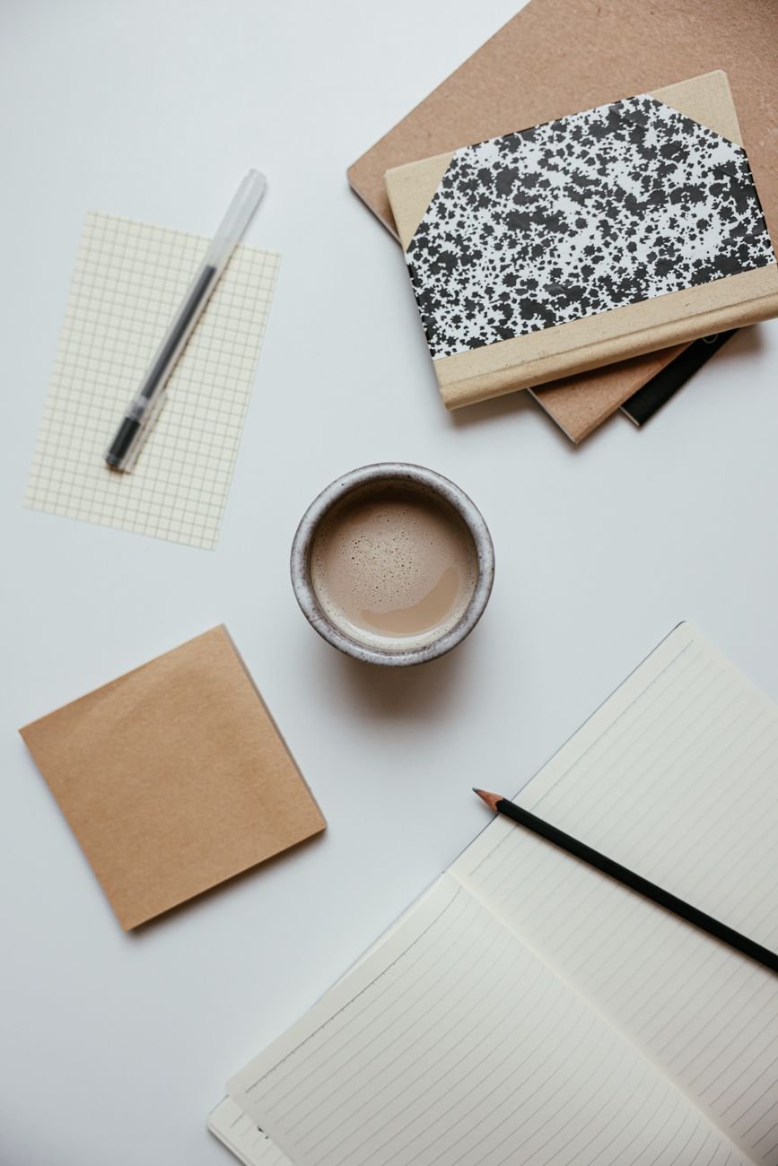 Minimalist flat lay of notebooks and stationery on a warm desk